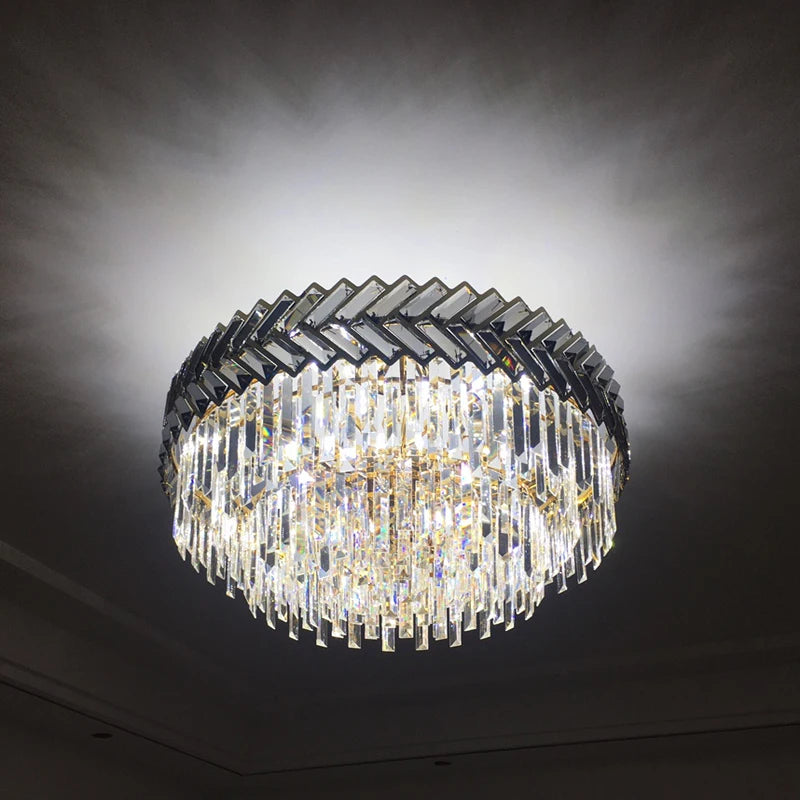 A gold-framed chandelier with clear cascading crystals, illuminated against a dark background to highlight its sparkle and design.