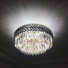 A gold-framed chandelier with clear cascading crystals, illuminated against a dark background to highlight its sparkle and design.