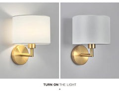 Two wall sconces with gold fixtures and white lampshades on a gray background.