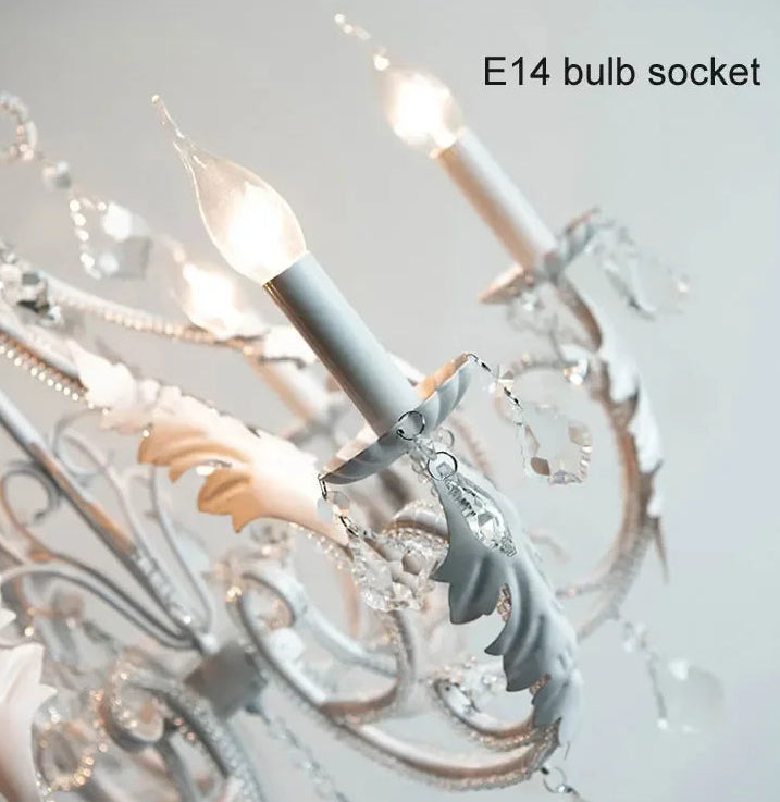 Close-up of an E14 bulb socket with decorative chandelier in the background