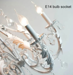 Close-up of an E14 bulb socket with decorative chandelier in the background