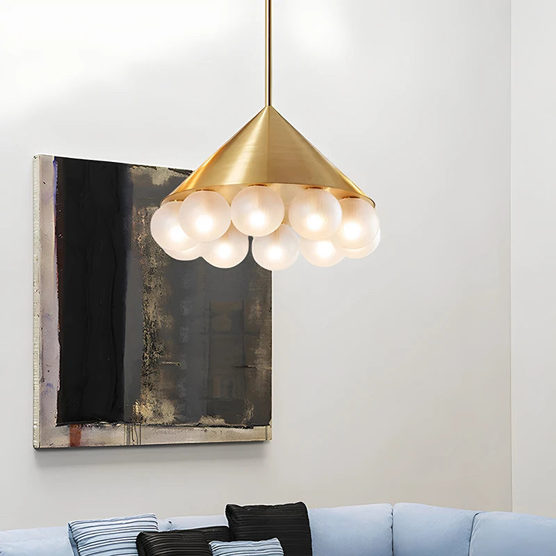 Gold pendant light fixture hanging above a sofa with a painting in the background