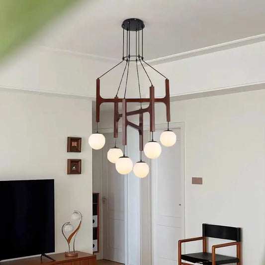A modern chandelier with a dark wood frame and six white globe shades, hanging from a black ceiling mount in a well-lit room.