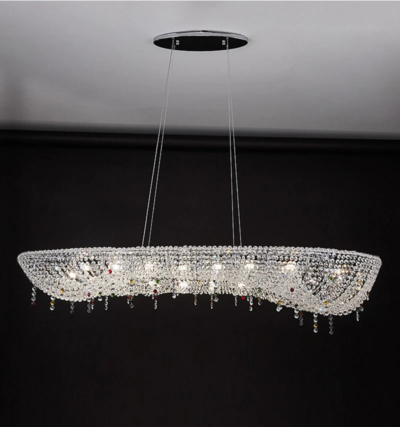 Close-up of an oval crystal chandelier with colorful accents hanging above a table.