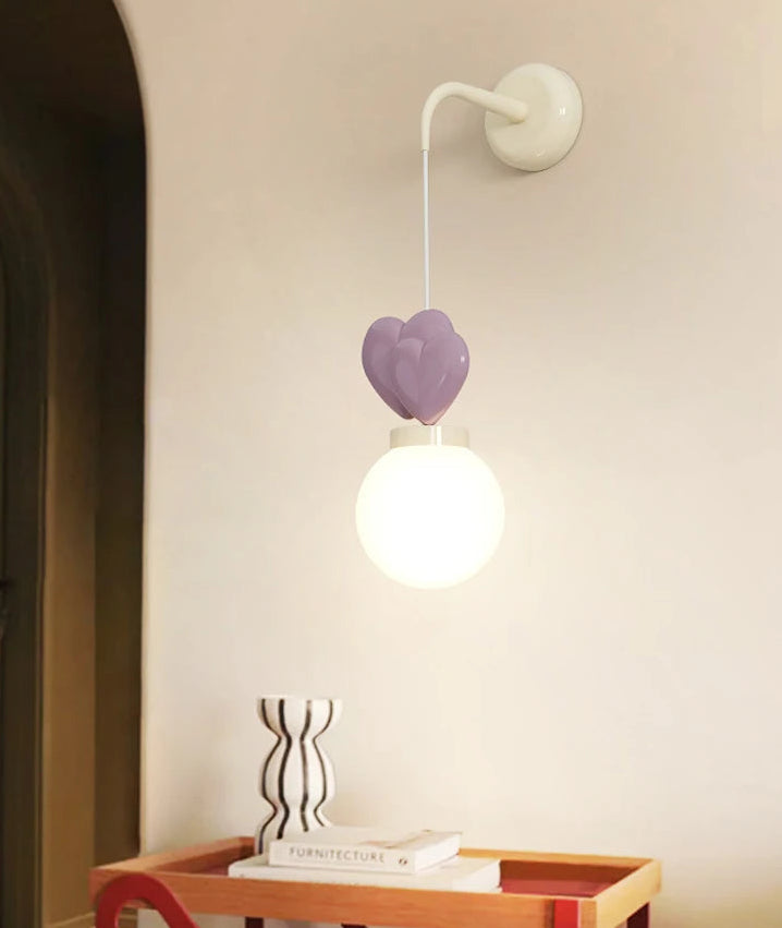 Wall-mounted lamp with a heart-shaped design on a light-colored wall.