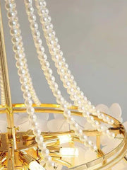 Decorative light fixture with pearls and gold accents on a neutral background