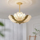 A transparent shell-shaped glass pendant light with gold leaf accents hanging from a decorative ceiling medallion.