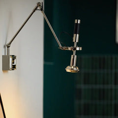 Close-up view of a polished chrome and black adjustable swing arm wall sconce with a silver finish.