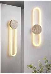 A modern wall sconce with a circular stone accent and a U-shaped yellow LED light, mounted on a white wall.