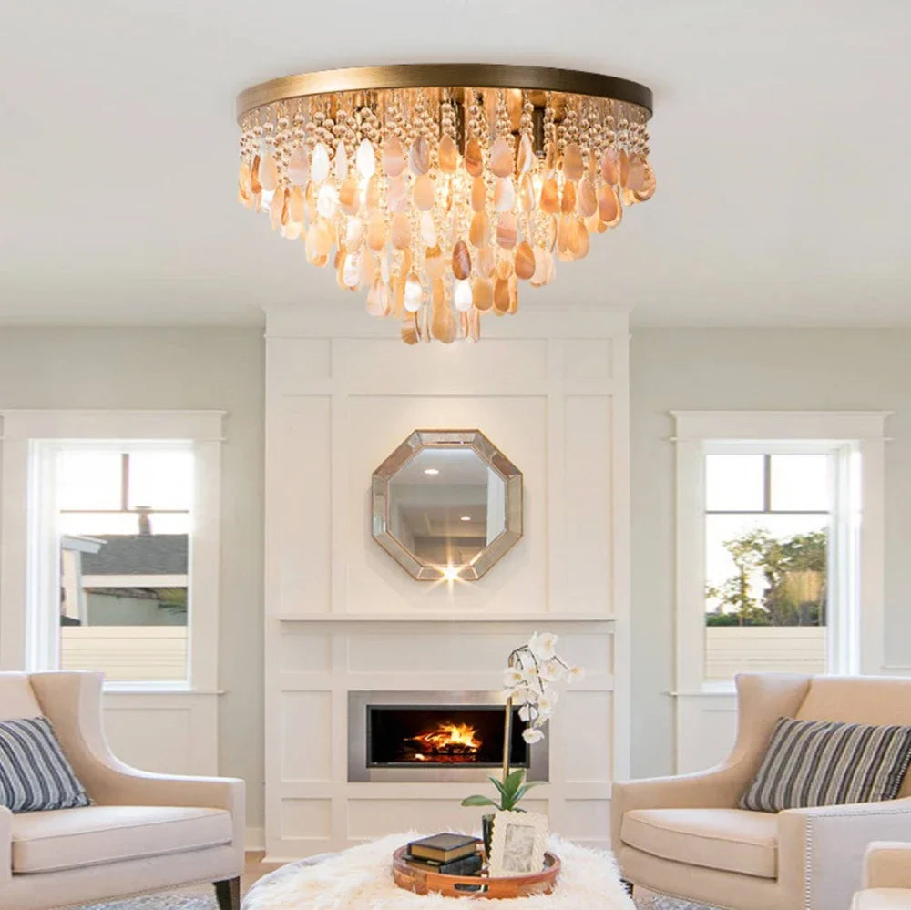 A gold and shell semi-flush mount ceiling light with multiple tiers of teardrop shapes hanging from a circular base, illuminating a living room with a fireplace.