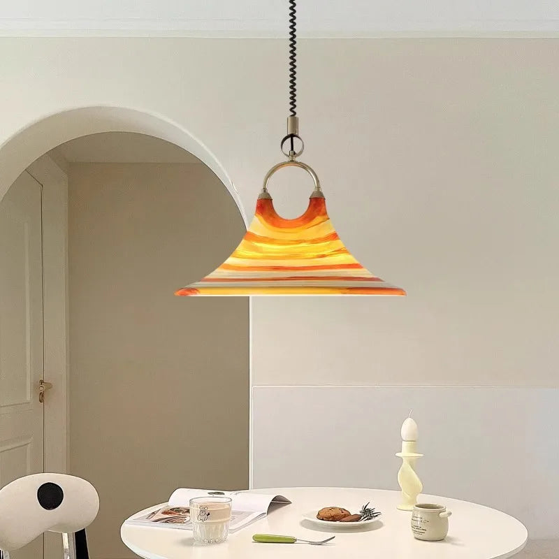 Pendant light with a colorful glass shade hanging above a dining table.