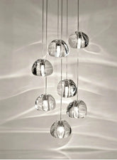 A cluster of clear crystal ball pendant lights hanging in a cascade, casting light patterns on the wall.