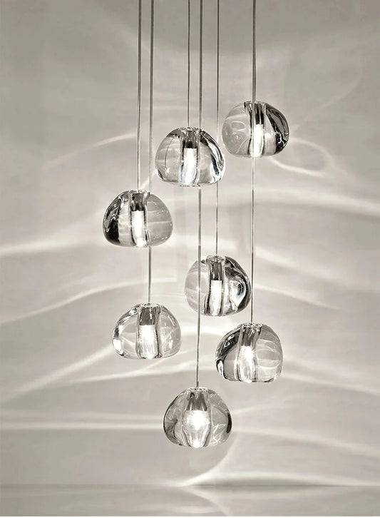 A cluster of clear crystal ball pendant lights hanging in a cascade, casting light patterns on the wall.