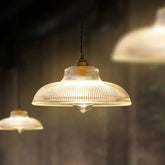 Close-up of a fluted glass dome pendant light with a polished copper accent hanging in a dimly lit room.