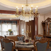 Brass tiered chandelier with cascading crystals hanging over a marble dining table.