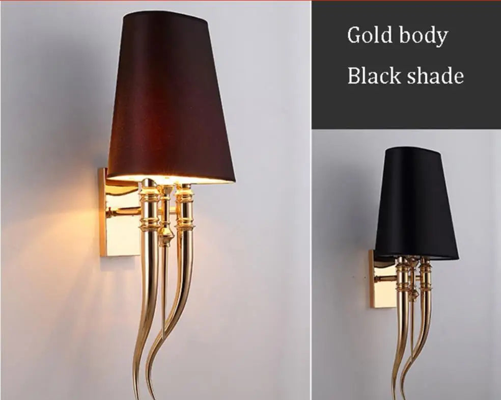 Wall sconce with gold body and black shade on a gray background