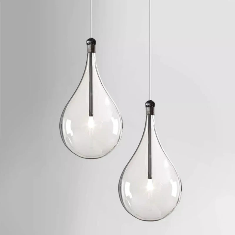 Two clear glass teardrop pendant lights hanging against a white background.