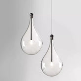 Two clear glass teardrop pendant lights hanging against a white background.