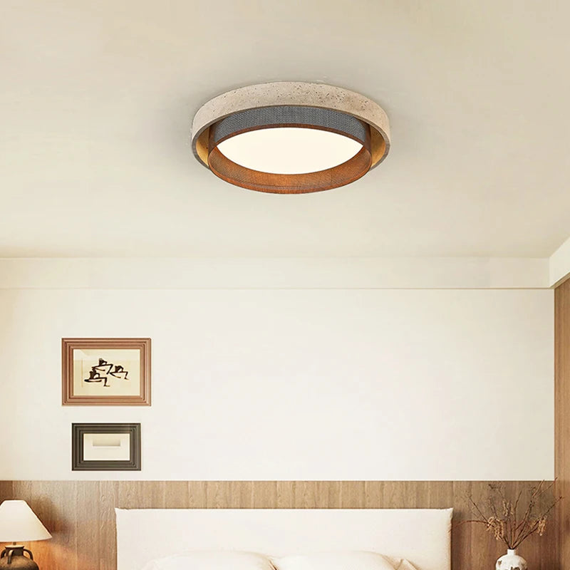 A bedroom ceiling with a decorative stone-textured ring flush mount light providing illumination.