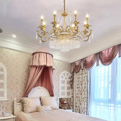 Brass crystal chandelier with pink canopy bed in a bedroom.