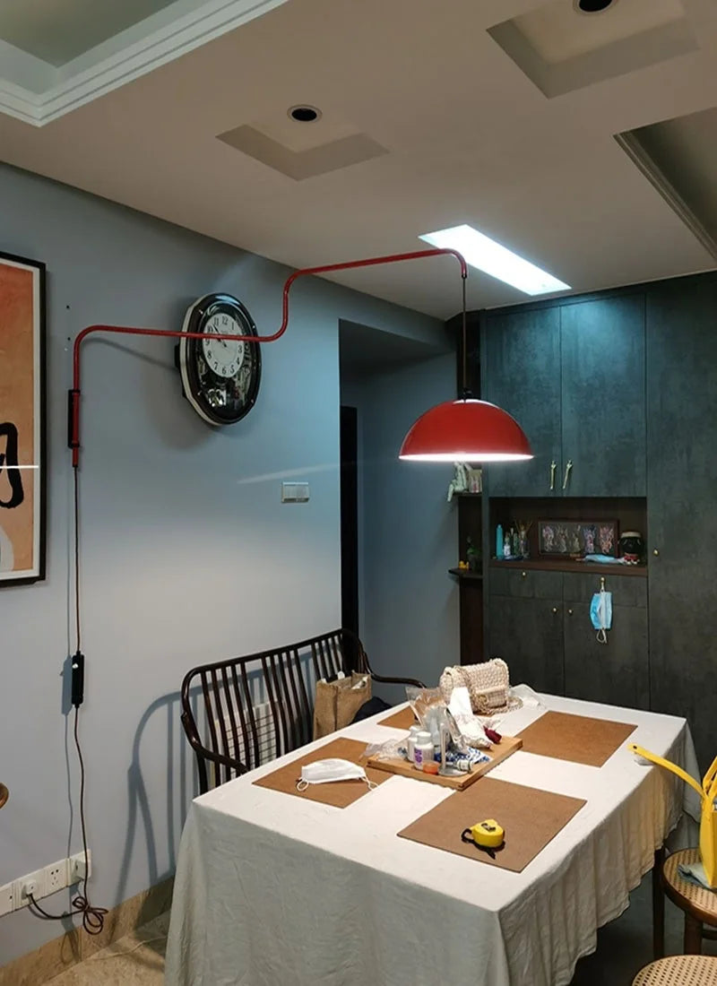 Dining area with a red pendant light, table set for a meal, and wall clock.