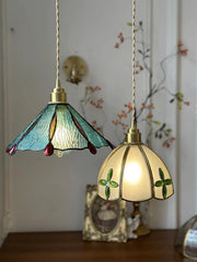 Two stained glass pendant lights on a wooden surface with a decorative background.