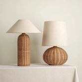 Two table lamps with woven rattan bases and fabric shades on a white tablecloth.