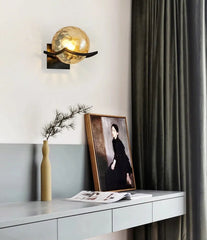Modern wall sconce with decorative frame and plant on a white wall.