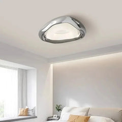A modern chrome wave ceiling light fixture installed in a well-lit bedroom.