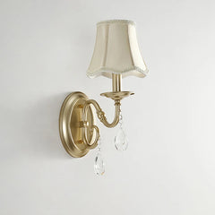 Wall-mounted light fixture with beige lampshade and crystal accents on a plain background