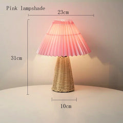 Pink pleated fabric shade table lamp with a woven rattan base, showing dimensions of 31cm height and 23cm shade width.