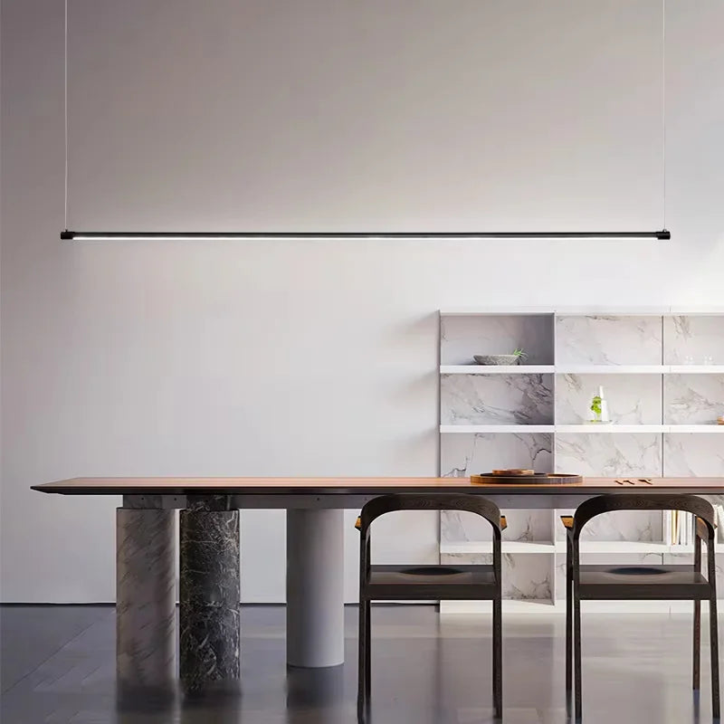 Black minimalist linear pendant light over a wooden dining table with marble-effect legs