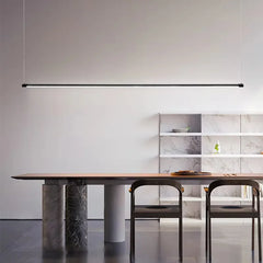 Black minimalist linear pendant light over a wooden dining table with marble-effect legs