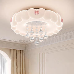 Angled view of a white cloud flush mount ceiling light with pink bows and crystal embellishments, installed in a room with soft lighting.