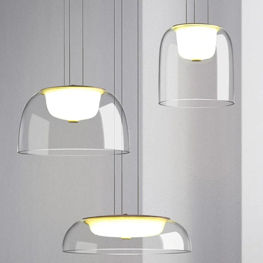 Three clear glass dome pendant lights with gold accents hanging against a light gray background.