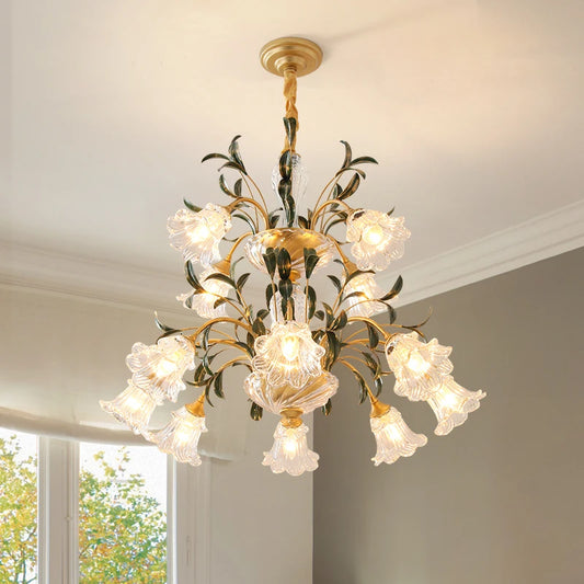 Close-up of a multi-arm gold chandelier with clear glass shades shaped like flowers, hanging from a ceiling.