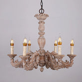 Close-up of a distressed wood chandelier with candelabra-style arms, intricate carvings, and detailed floral accents against a white background.