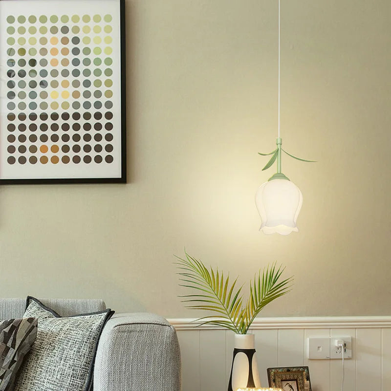 A flower pendant light hanging in a living room setting, with a grey sofa and a piece of abstract art on the wall.