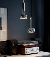 Modern interior with a turntable, speakers, and hanging pendant lights against a dark wall.