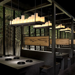 Modern restaurant interior with wooden walls, tables, and pendant lights.
