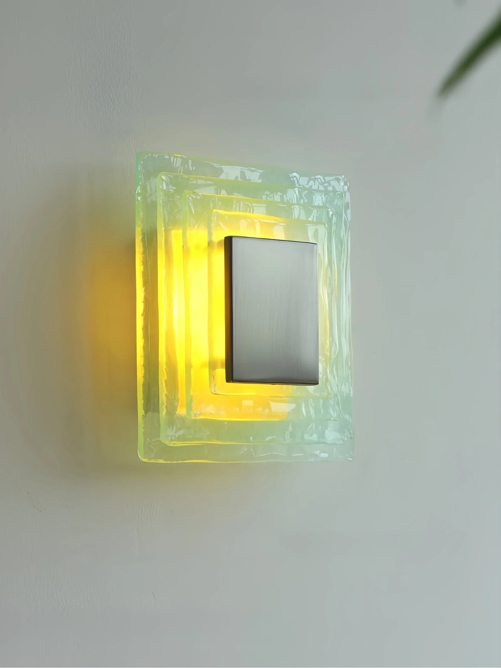 Decorative wall light fixture with a glowing yellow interior on a white wall.