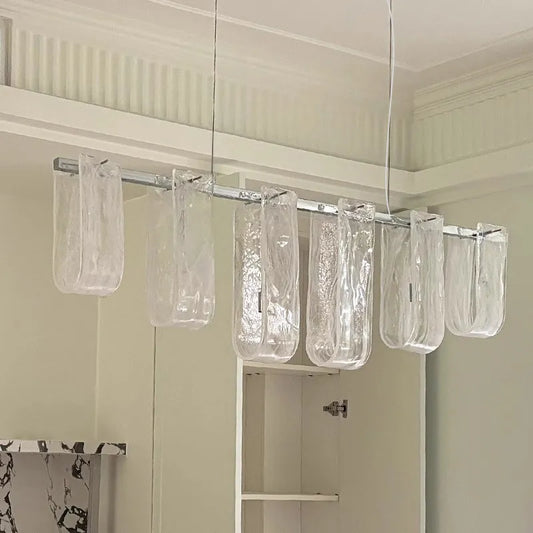 Linear pendant light with multiple clear glass tubes hanging from a metal bar