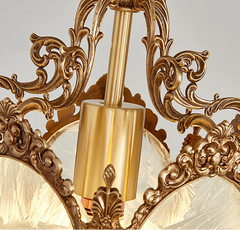 Decorative gold light fixture with intricate designs on a gray background.