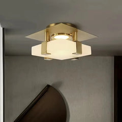 Side view of a gold flush mount ceiling light with a square base and a faceted crystal diffuser.