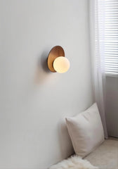 A dimly lit bedroom scene featuring a wood arc wall sconce with a frosted glass globe above a pillow.