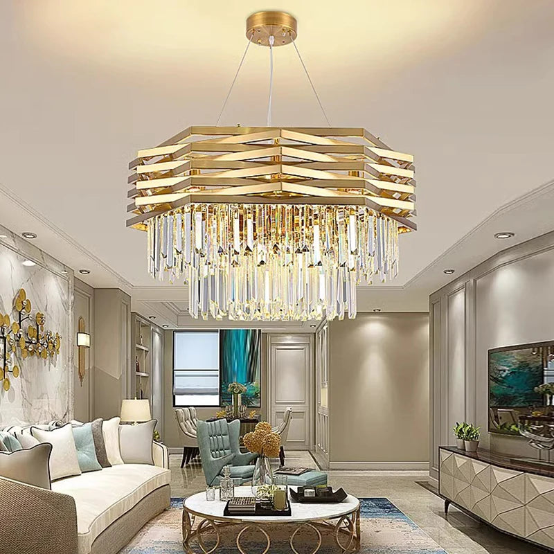 A spacious living room featuring a gold tiered crystal chandelier above a circular coffee table and a sectional sofa.