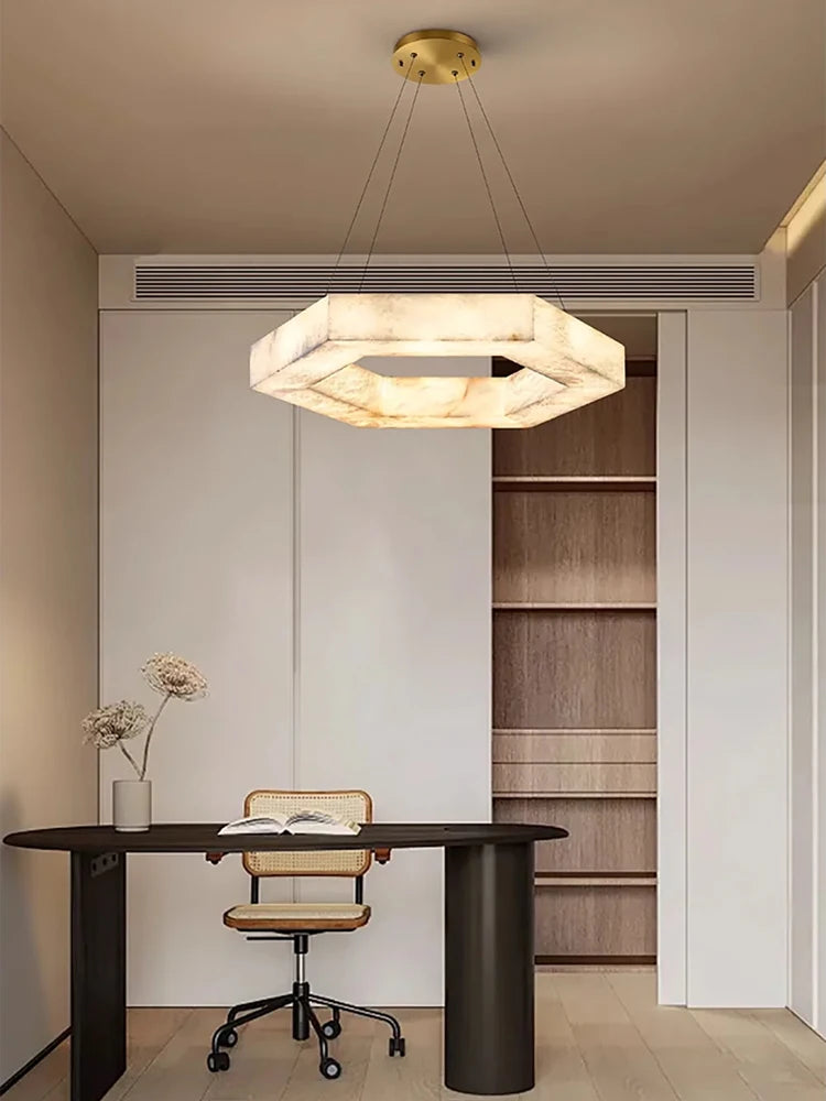 Modern office space with a chandelier, desk, and chair.