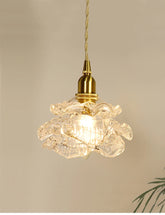 Close-up of a brass-finished pendant light with a clear glass shade shaped like a blooming flower.