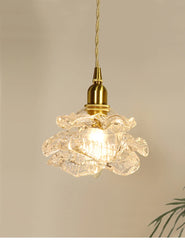 Close-up of a brass-finished pendant light with a clear glass shade shaped like a blooming flower.