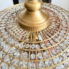Detailed view of the intricate metalwork and sparkling crystals of a large, round chandelier.